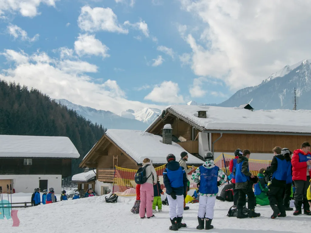 Gruppe versammelt sich vor einem Holzhaus im Schnee.